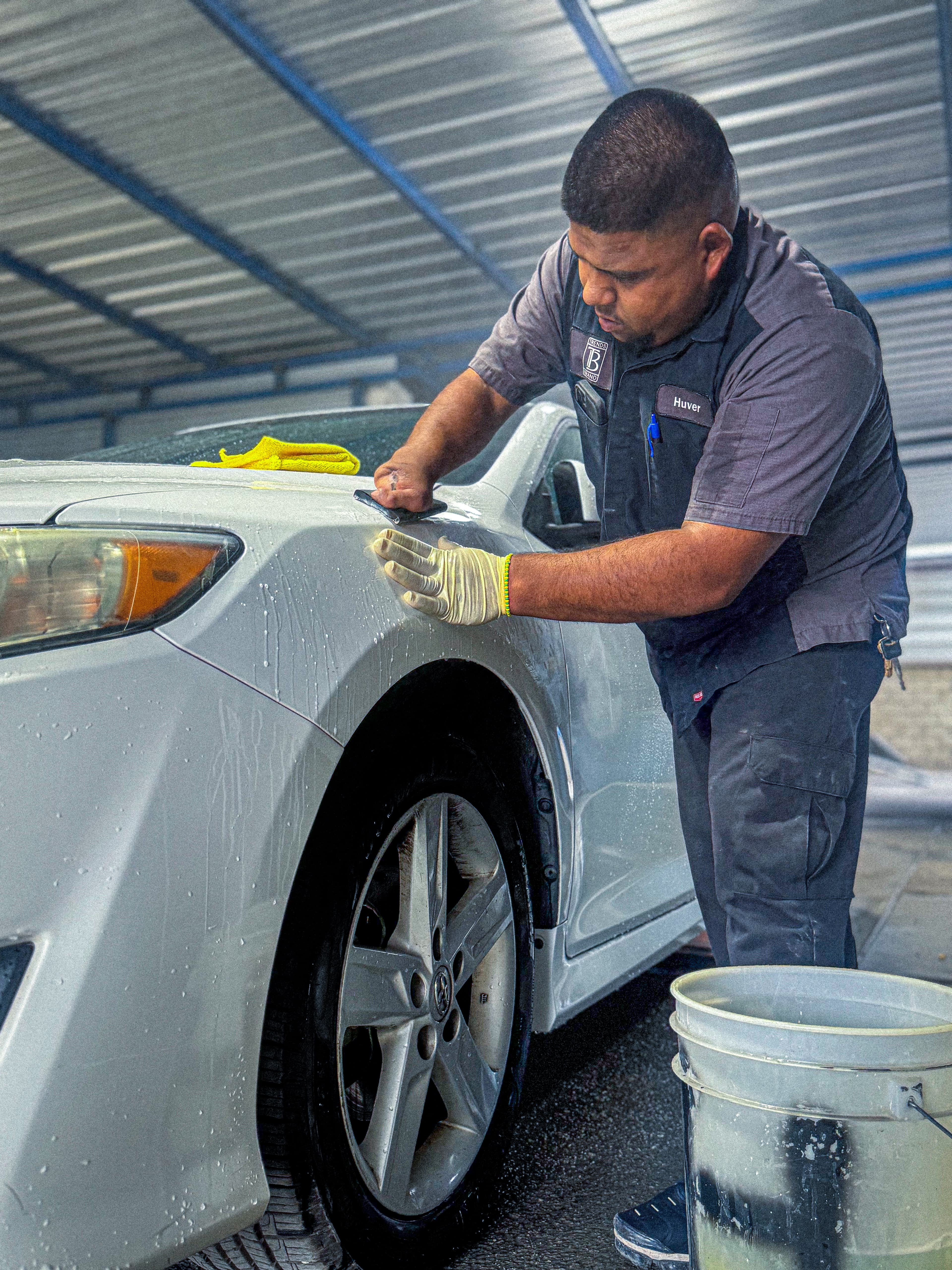 Trends technician carefully working on the front panel of a white car